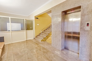 A hotel lobby with a marble floor, an elevator, and a staircase leading to the third floor. - Collection O Goyal Residency (Bangalore)