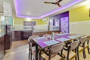 A conference room with a long table, chairs, and a ceiling fan. - Collection O Goyal Residency (Bangalore)