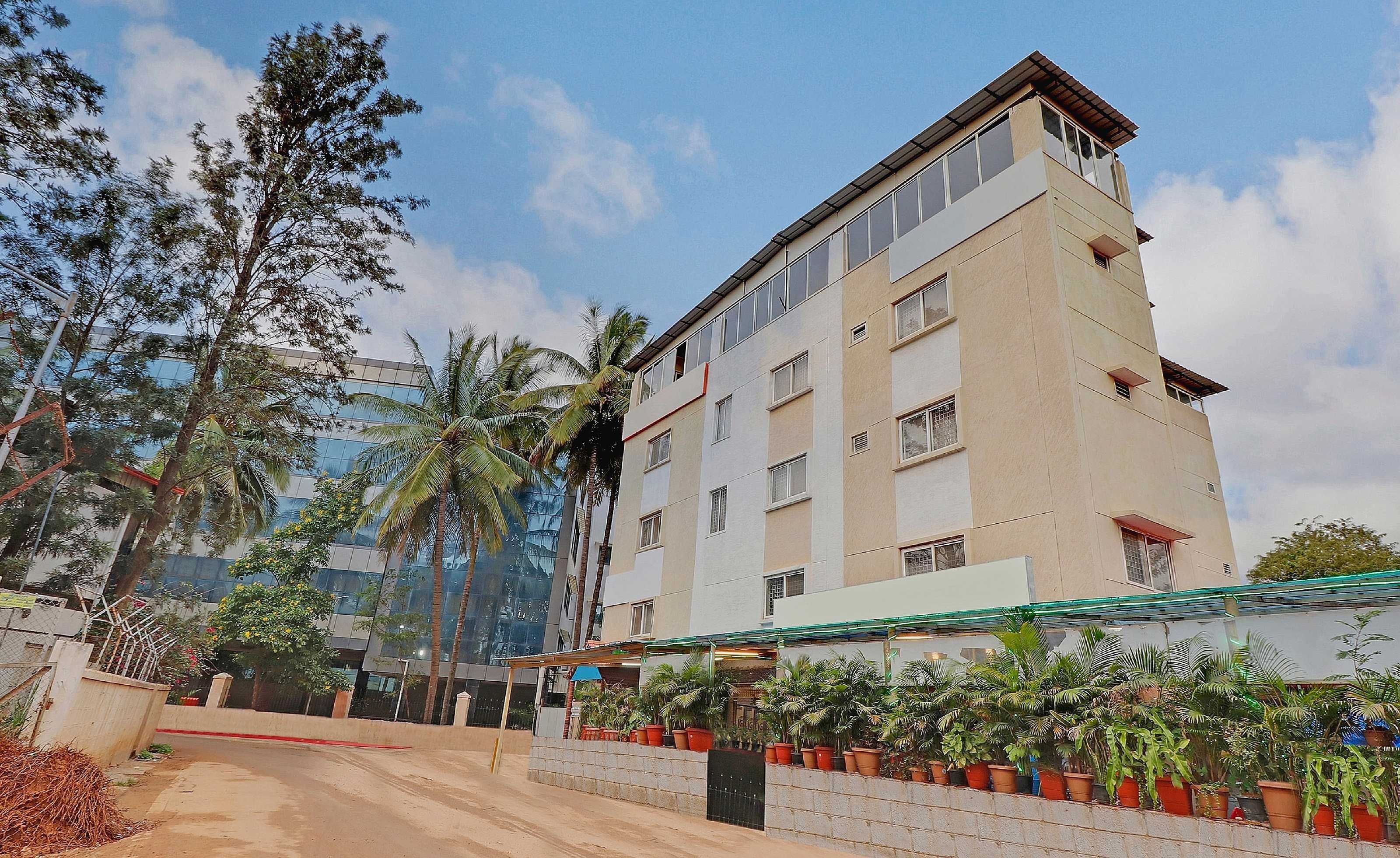 A multi-story hotel with a flat facade, large windows, and a rooftop terrace.