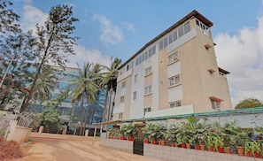 A multi-story hotel with a flat facade, large windows, and a rooftop terrace. - Collection O Goyal Residency (Bangalore)