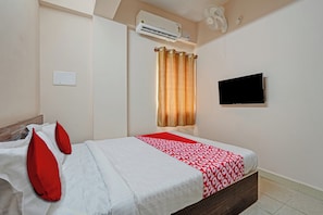 A hotel room with a bed, a flat-screen TV, an air conditioning unit, and a window with curtains. - Hotel O Sri Ranga Boarding & Lodging (Bangalore)
