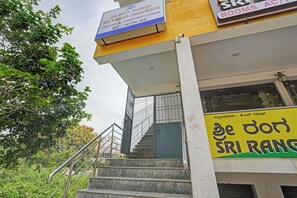 A staircase leading to a building with signage indicating rooms and AC availability. - Hotel O Sri Ranga Boarding & Lodging (Bangalore)
