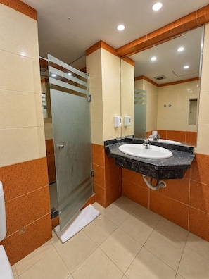 A bathroom with a glass door shower, a sink with a marble countertop, and a mirror above the sink. - Davinci Beach Hotel (Red Sea Governorate)