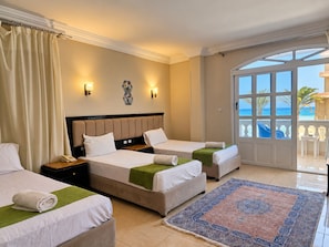 A hotel room with two beds, a large window with a view of the sea, and a balcony with outdoor furniture. - Davinci Beach Hotel (Red Sea Governorate)