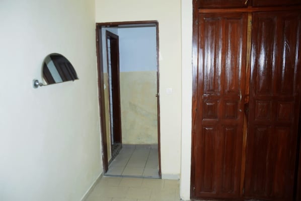 A hallway with a wooden door and a mirror on the wall. - New Listing (Yaoundé)