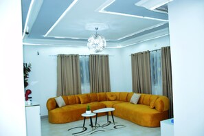 Un salon moderne avec un canapé d’angle, un lustre et une petite table.