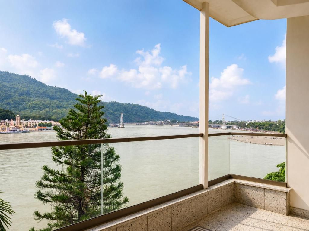 A balcony with a view of a river, a bridge, and a distant hill.