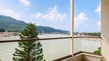 A balcony with a view of a river, a bridge, and a distant hill.