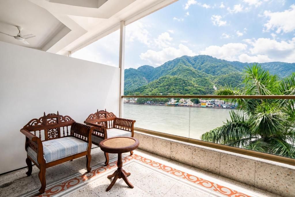 A balcony with a view of a river and mountains, furnished with a sofa and a small table.