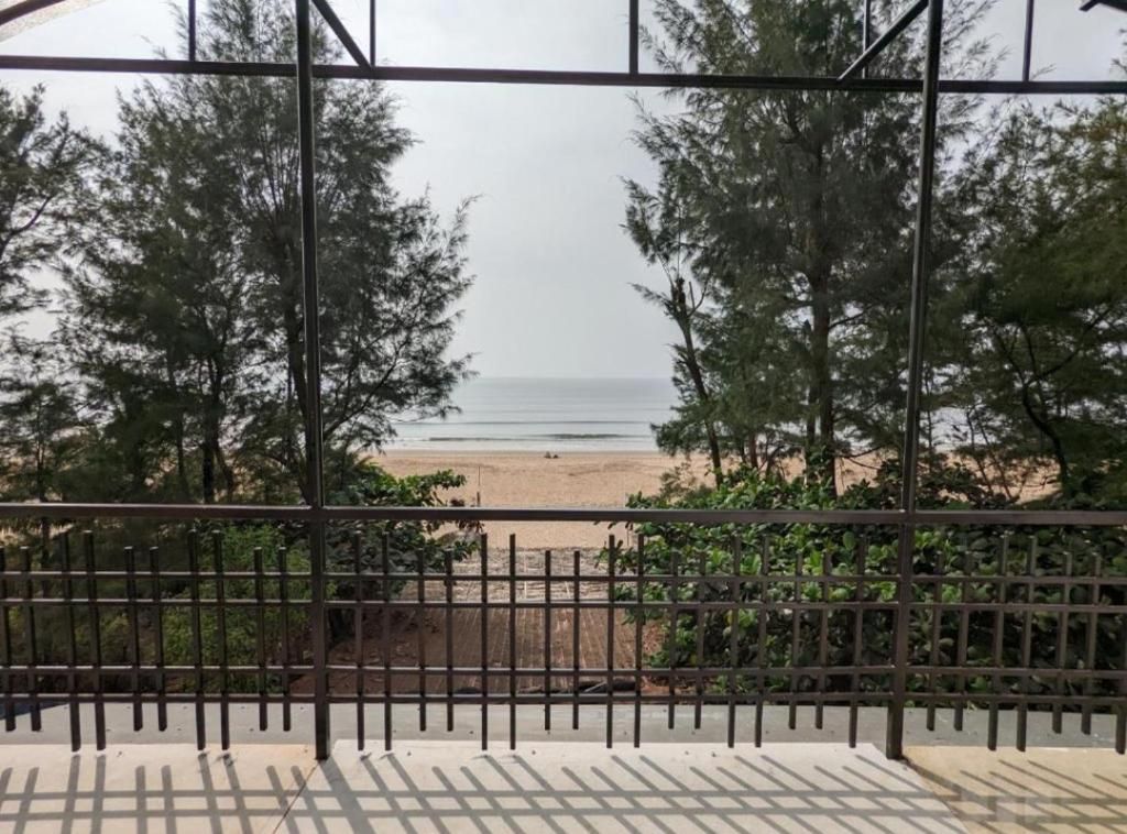 A view through a metal railing with a beach and ocean in the background.