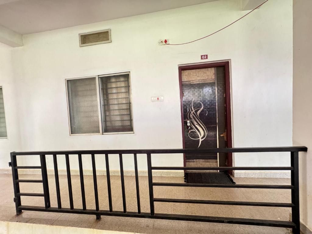 Passadís amb barana de metall negre, una porta amb un panell de vidre decoratiu i una finestra amb reixatge metàl·lic.