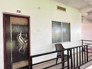 A building entrance with a door marked 'G1,' a window, and a chair outside. - Surya Beach Cafe And Stay (Gokarna)