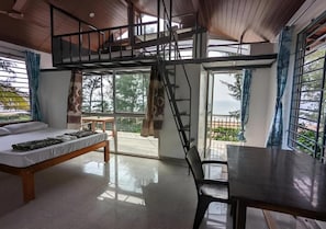 A bedroom with a bed, a desk, and a balcony with a view. - Surya Beach Cafe And Stay (Gokarna)