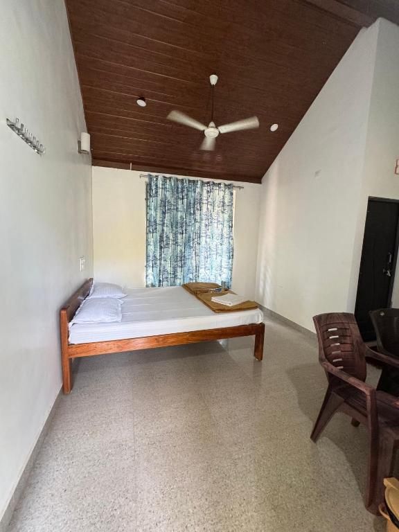 Una habitació amb un llit, un ventilador de sostre, una finestra amb cortines i una porta.