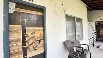 Una habitació amb una porta de fusta, una cadira i una escala.