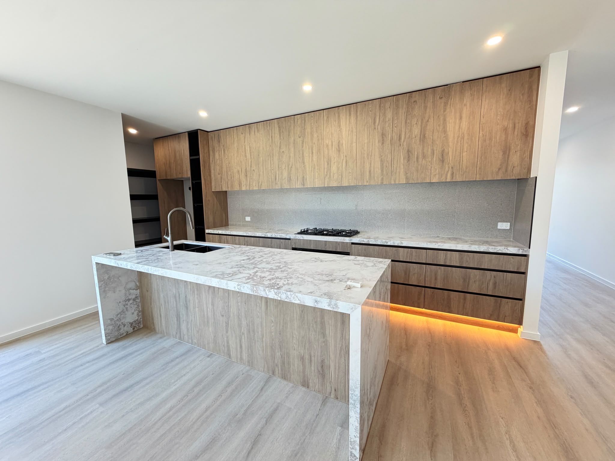 Una cocina moderna con encimera de mármol, armarios de madera y estufa integrada.