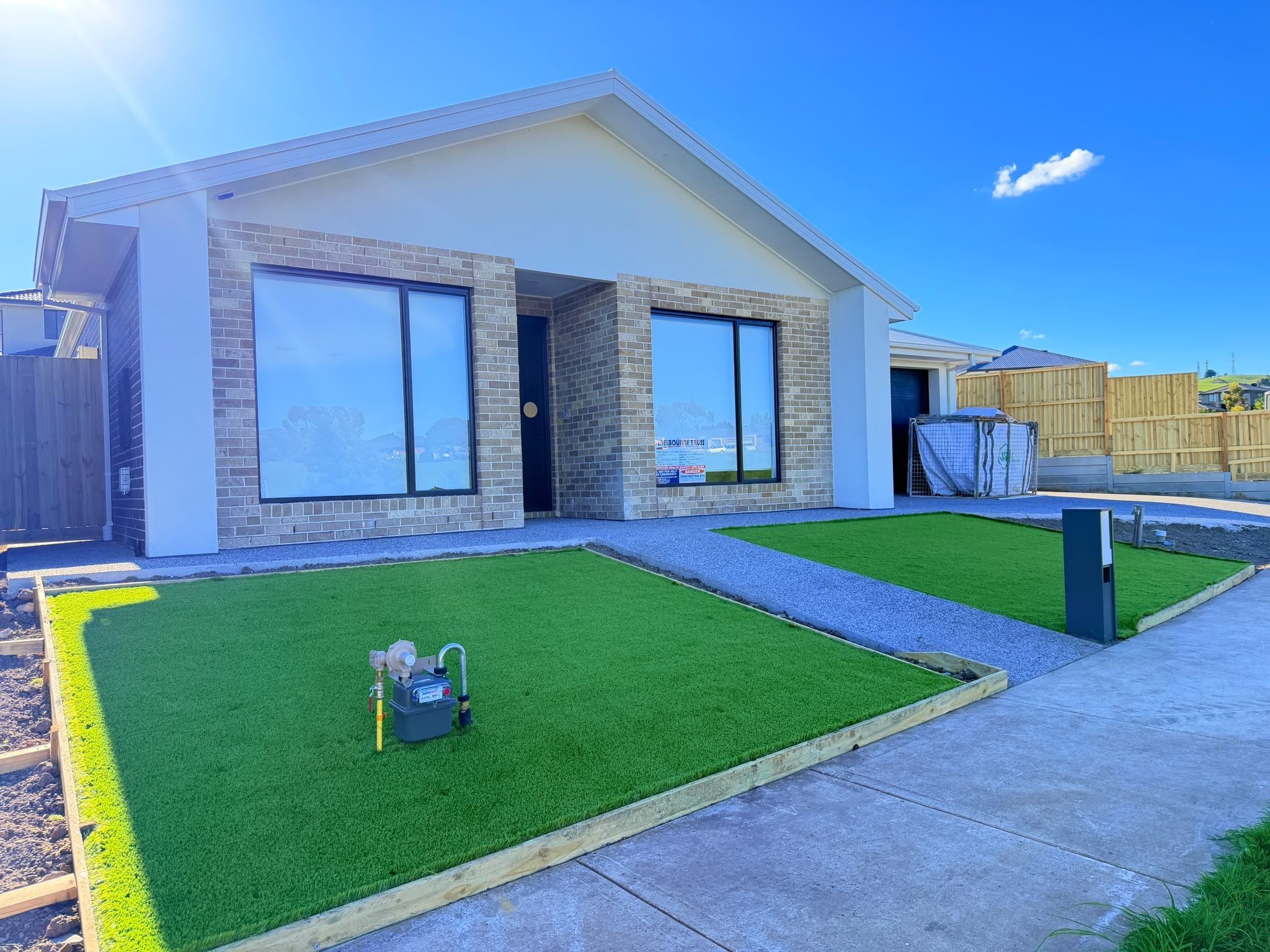 A modern two-story house with a large front yard, a garage, and a fenced backyard.