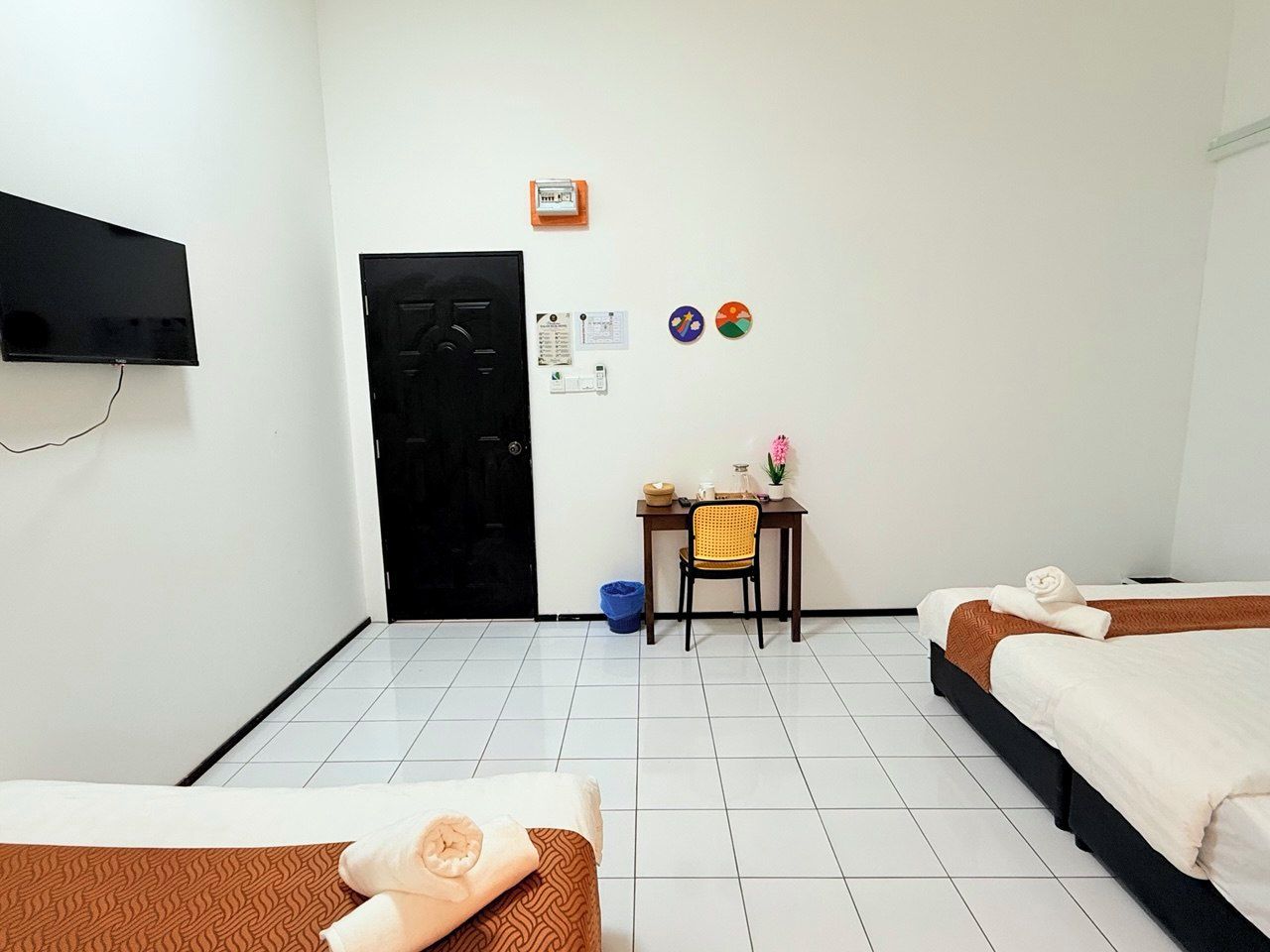 Habitación de hotel con dos camas, un escritorio, una silla, un televisor y una puerta.