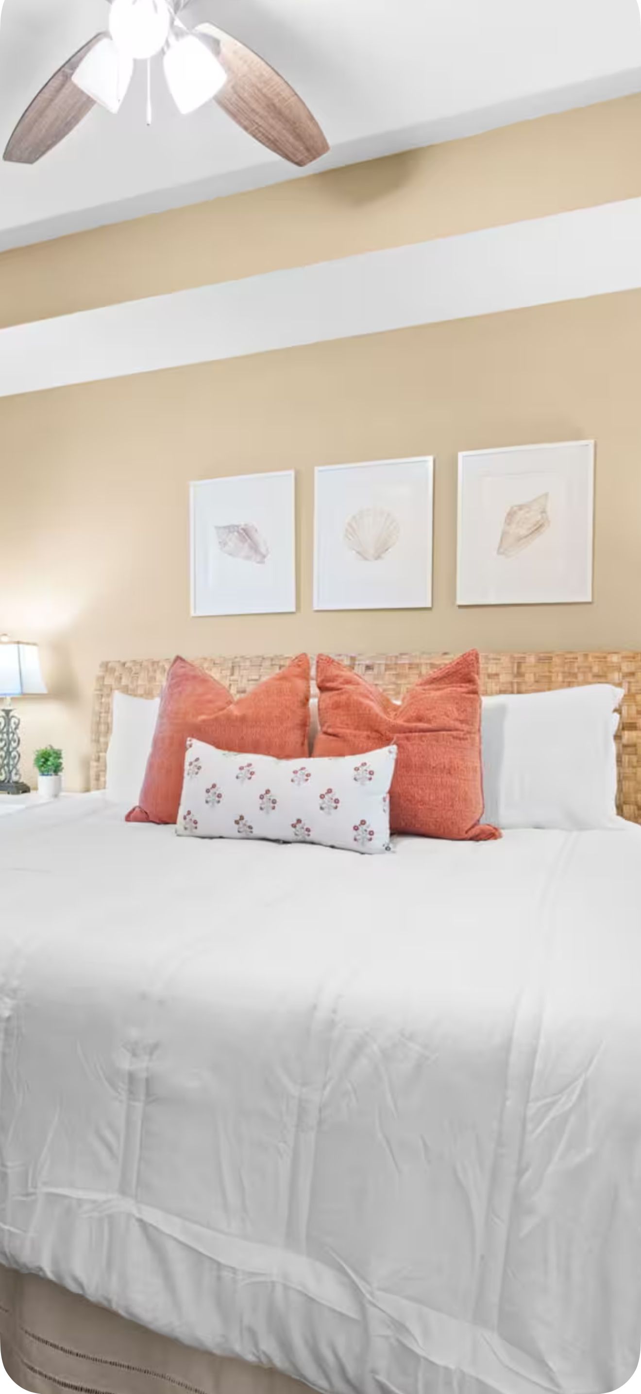Een slaapkamer met een bed, kussens en wanddecoratie.
