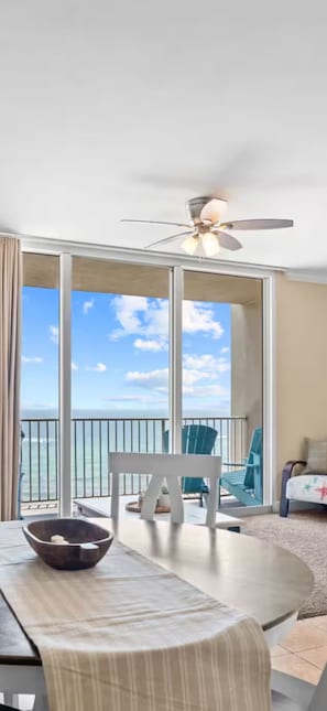 Ein Balkon mit Meerblick, ein Deckenventilator und ein Esstisch mit Stühlen.