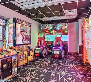 Ein Raum mit Spielautomaten, darunter ein Motorrad-Rallye-Spiel und eine Spiele-Tür-Maschine.