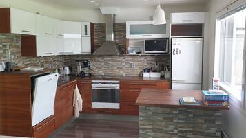 Une cuisine moderne avec des meubles blancs, un four encastré, un four à micro-ondes et un réfrigérateur.