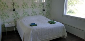 Une chambre à coucher avec un lit, deux lampes de chevet, une table de chevet et une fenêtre.