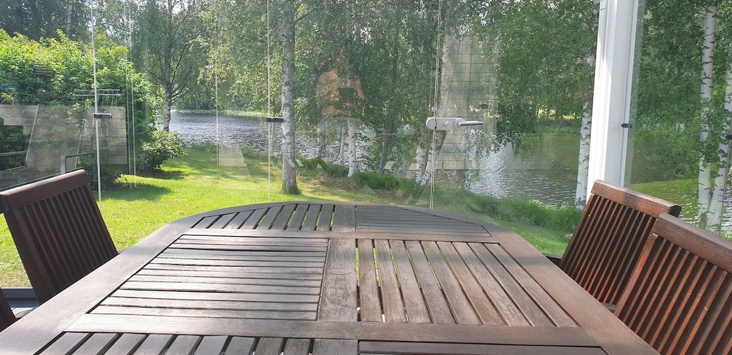 A wooden table and chairs with a view of a river and greenery.