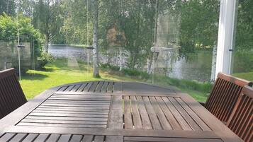 A wooden table and chairs with a view of a river and greenery.