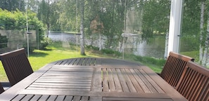 Une table et des chaises en bois, avec vue sur une rivière et la verdure environnante.