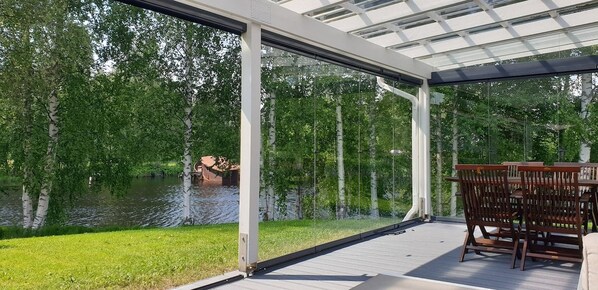 Une terrasse extérieure couverte avec vue sur un lac et des arbres.