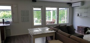 A living room with a sofa, a table, and a window overlooking a patio area. - River landscape close to the centre, Himos 8km (Jämsä)