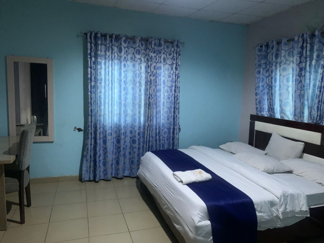 A hotel room with a bed, a desk, and curtains.
