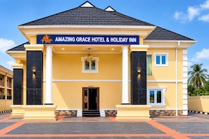 Um edifício de dois andares com uma placa indicando 'AMAZING GRACE HOTEL & HOLIDAY INN'.
