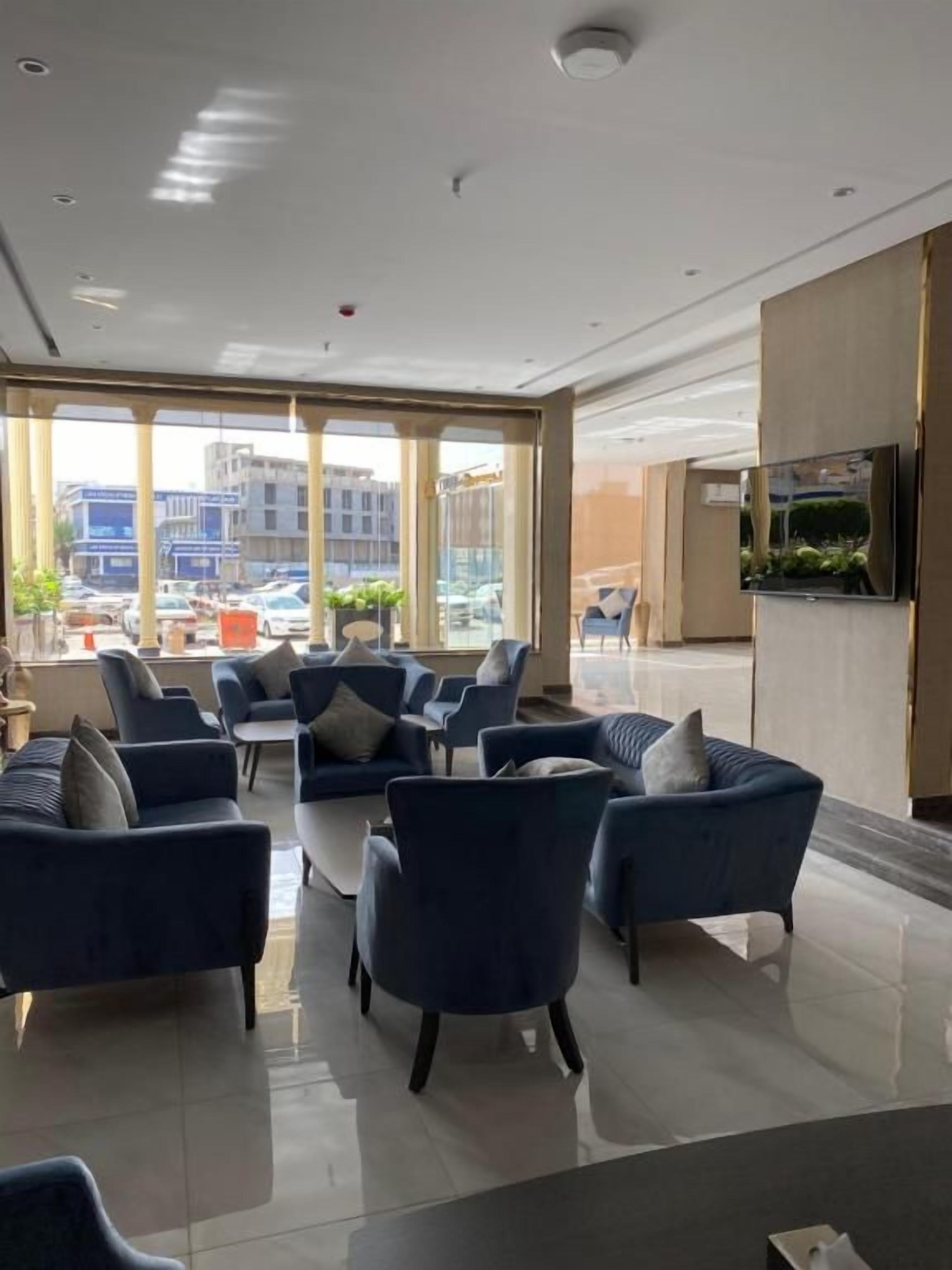 Un moderno vestíbulo de hotel con zona de estar, ventanas amplias y un televisor de pantalla plana.