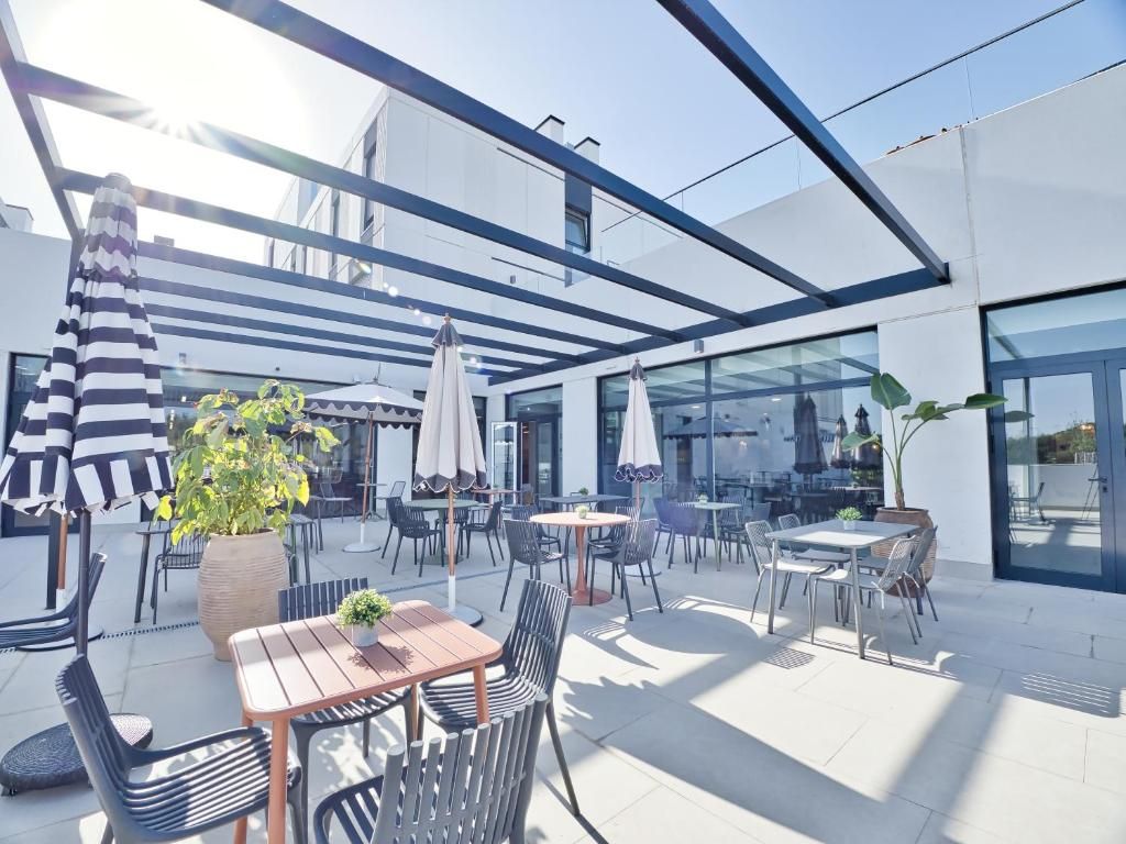 An outdoor patio area with tables and chairs, umbrellas, and potted plants.