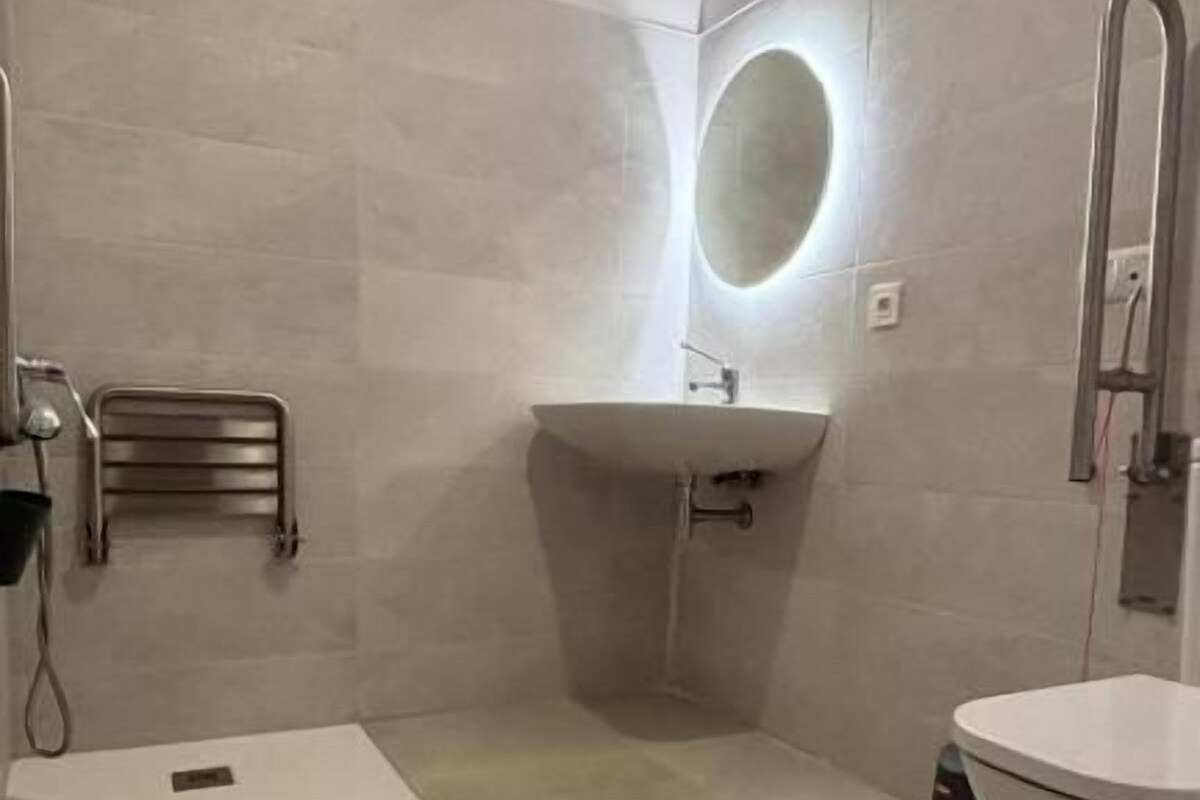 A modern bathroom with a shower, toilet, and sink.