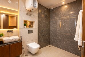 Un baño moderno con ducha de mármol, lavamanos integrado y retrete.