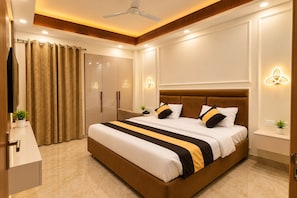 Un dormitorio de hotel moderno con una cama grande, mesitas de noche, un armario y un ventilador de techo.