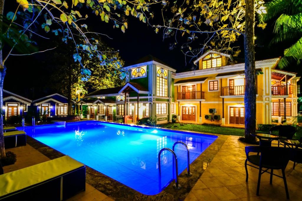 Una piscina con superficie de agua azul cristalina, rodeada por un área exterior bien iluminada y un edificio grande al fondo.