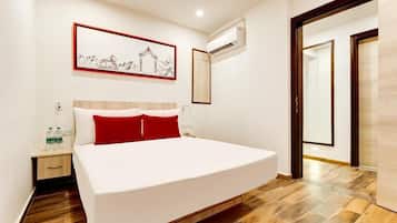 Habitación de hotel con cama, mesita de noche y unidad de aire acondicionado de pared.