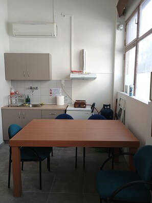 Een kleine keuken met een eettafel, stoelen en basisvoorzieningen zoals een spoelbak en kastjes.