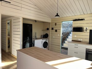 Une cuisine moderne avec un plan de travail en bois, un lave-linge et un four à micro-ondes.
