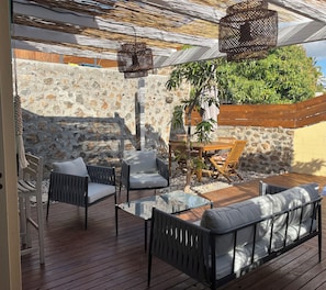 An outdoor patio with wicker furniture, a stone wall, and a wooden deck. - New Listing (Saint-Paul)