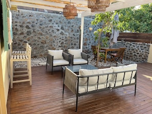 A wooden deck with outdoor furniture, a stone wall, and a hanging light fixture. - New Listing (Saint-Paul)