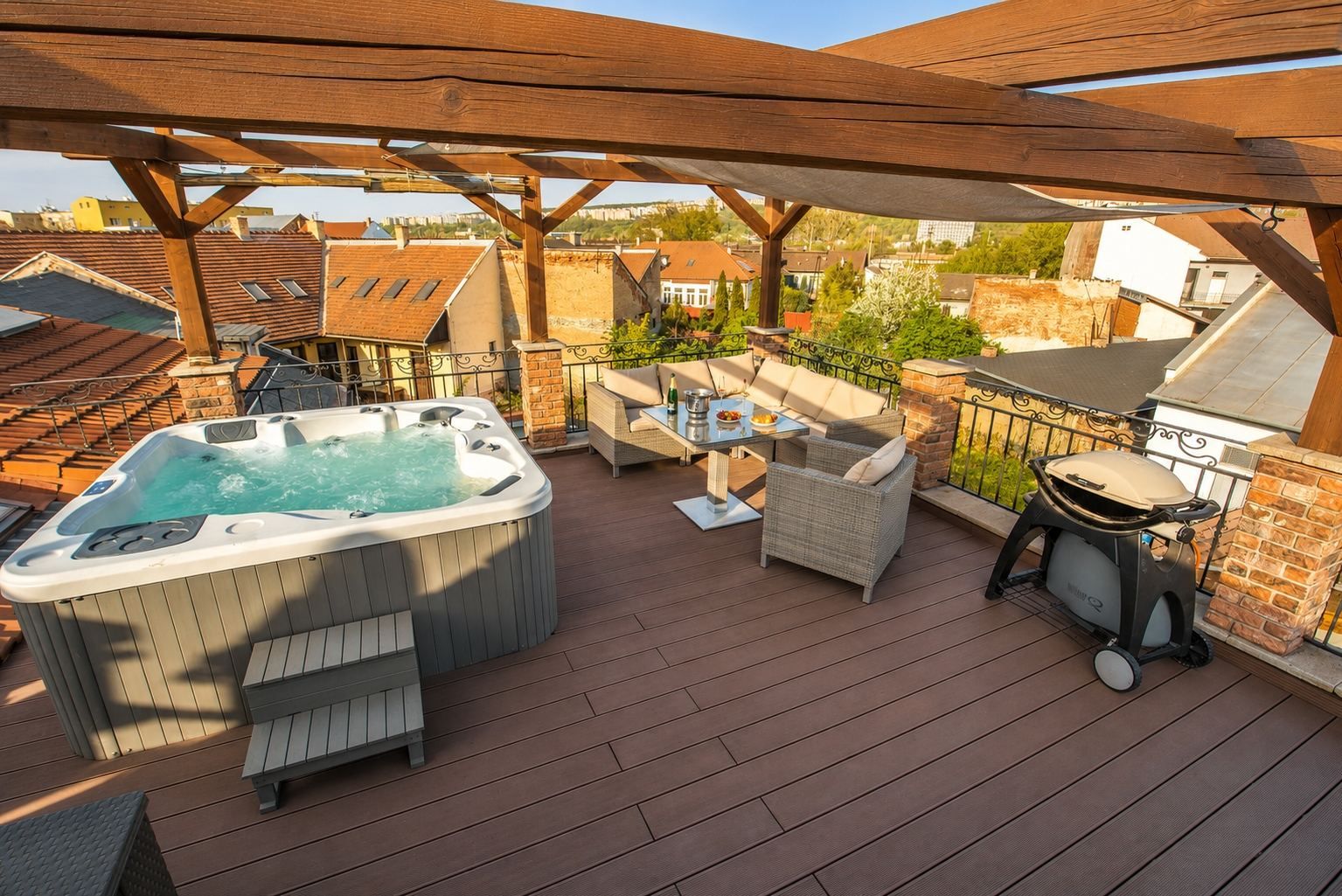 Una terraza en la azotea con jacuzzi, mobiliario exterior y una parrilla.