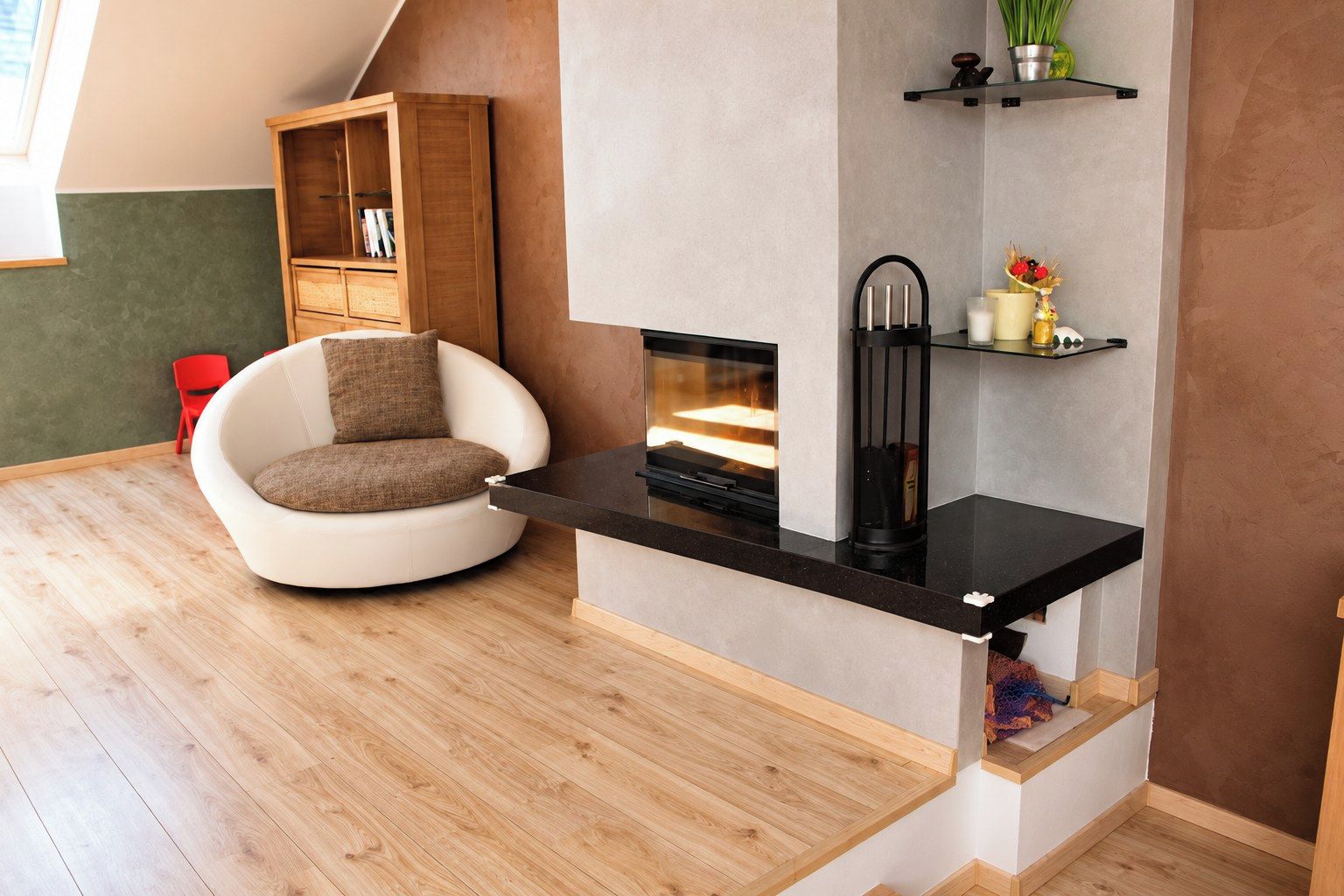 Una sala de estar moderna con chimenea empotrada, una estantería de madera, un sillón rojo y un sofá blanco redondo.
