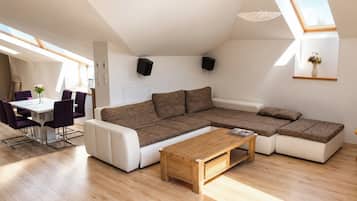 Um espaço de estar moderno com sofá modular, mesa de jantar com cadeiras e um claraboia.