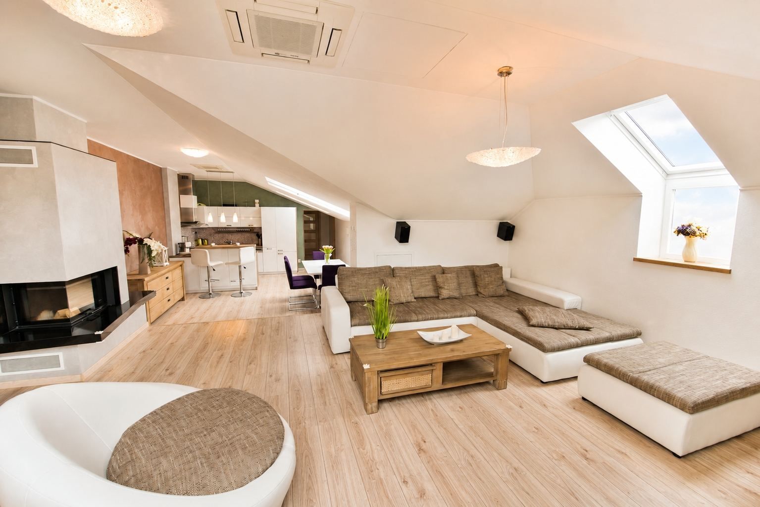 Een ruime woonkamer met een moderne bank, een eettafel en een keuken op de achtergrond.
