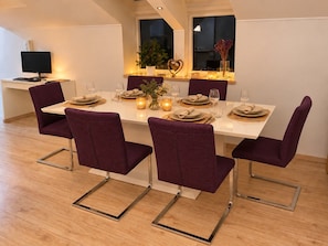 A dining area with a white table set for six, purple chairs, and a small potted plant on the windowsill. - Cassovia City Park Residence (Košice)